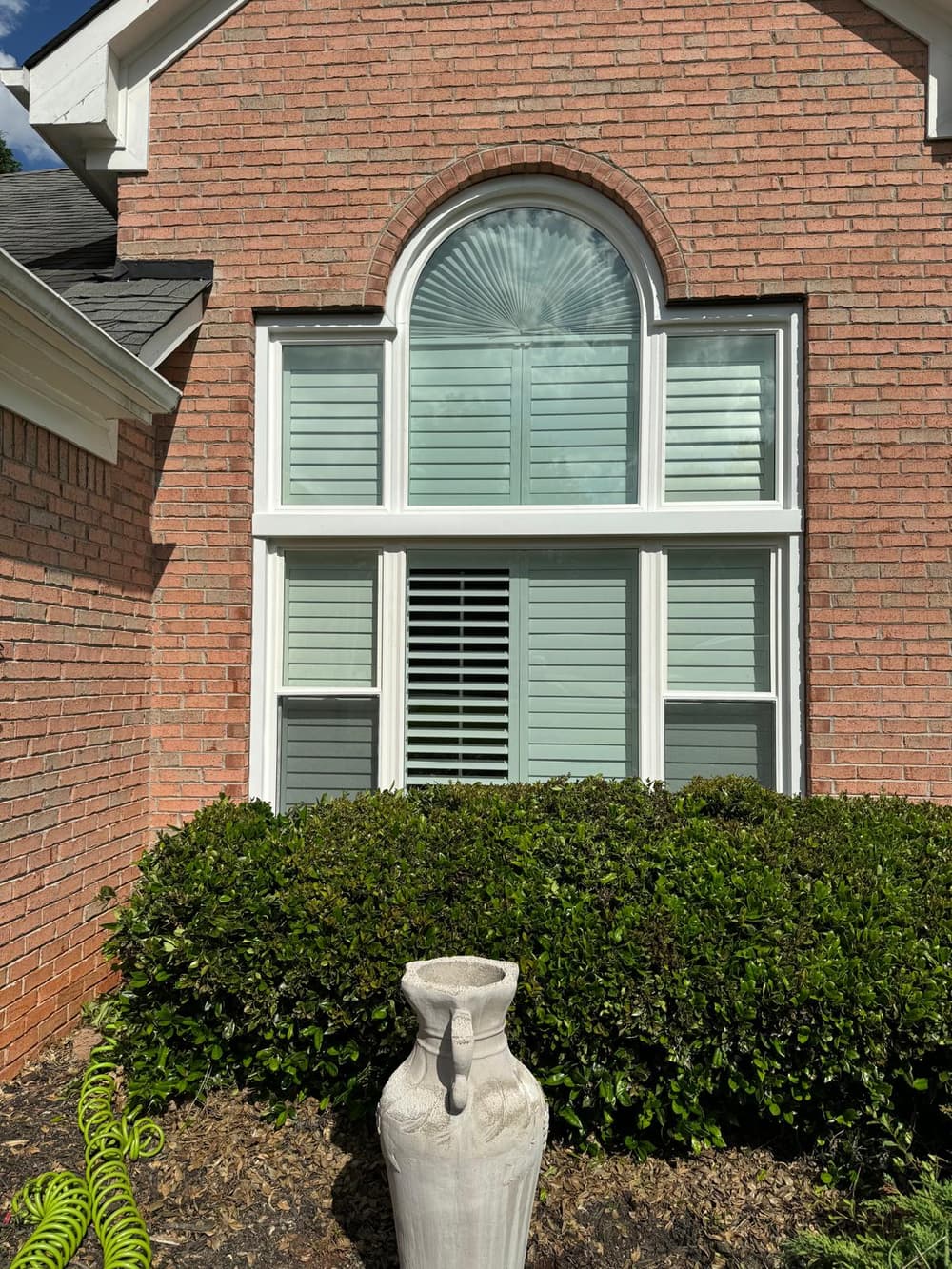 Finished arched window over a three-lite unit in a red brick gable