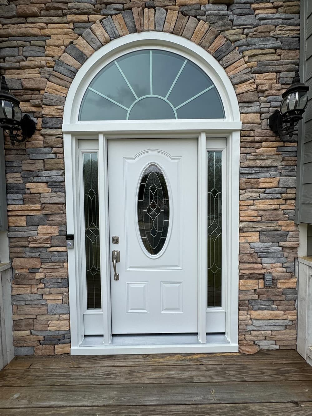 White entry door with oval glass, sidelites and a half-round transom in a stone front